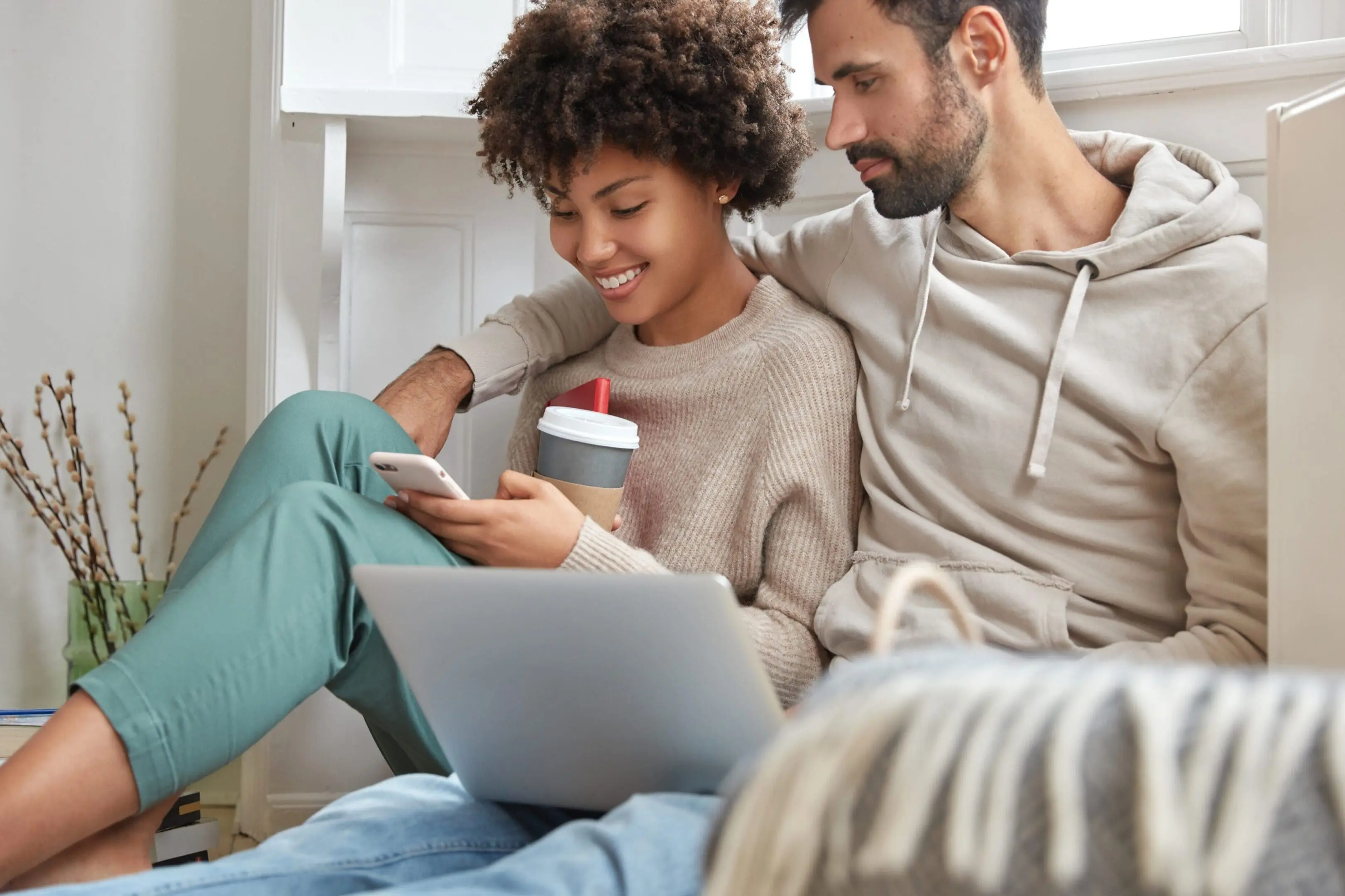 Man and woman sitting on a couch, both looking at a laptop