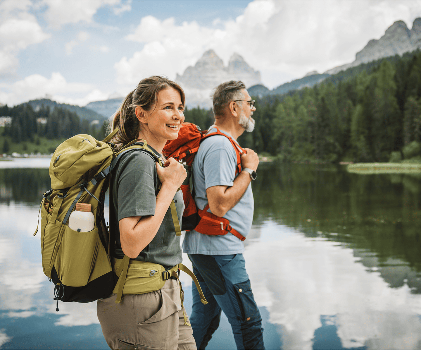 Two hikers walking by a scenic lake.