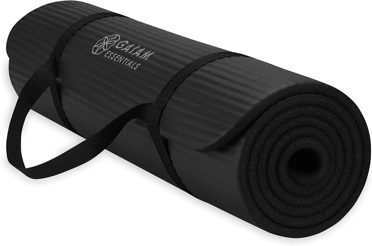 Black gaiam essentials yoga mat rolled up on a white background, with a black strap attached to it