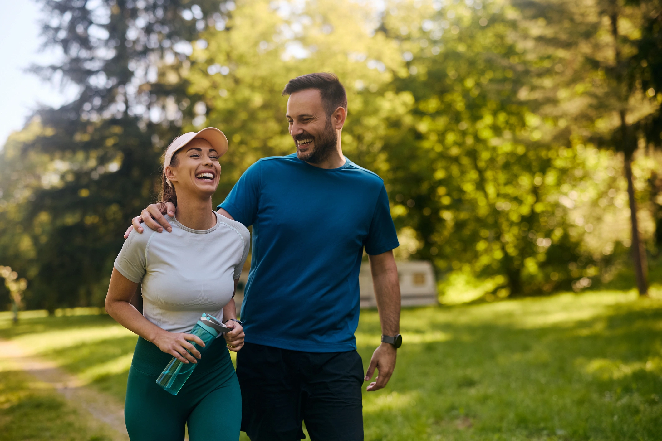 Man and woman jogging in the park, both of them and holding bottles in their hands