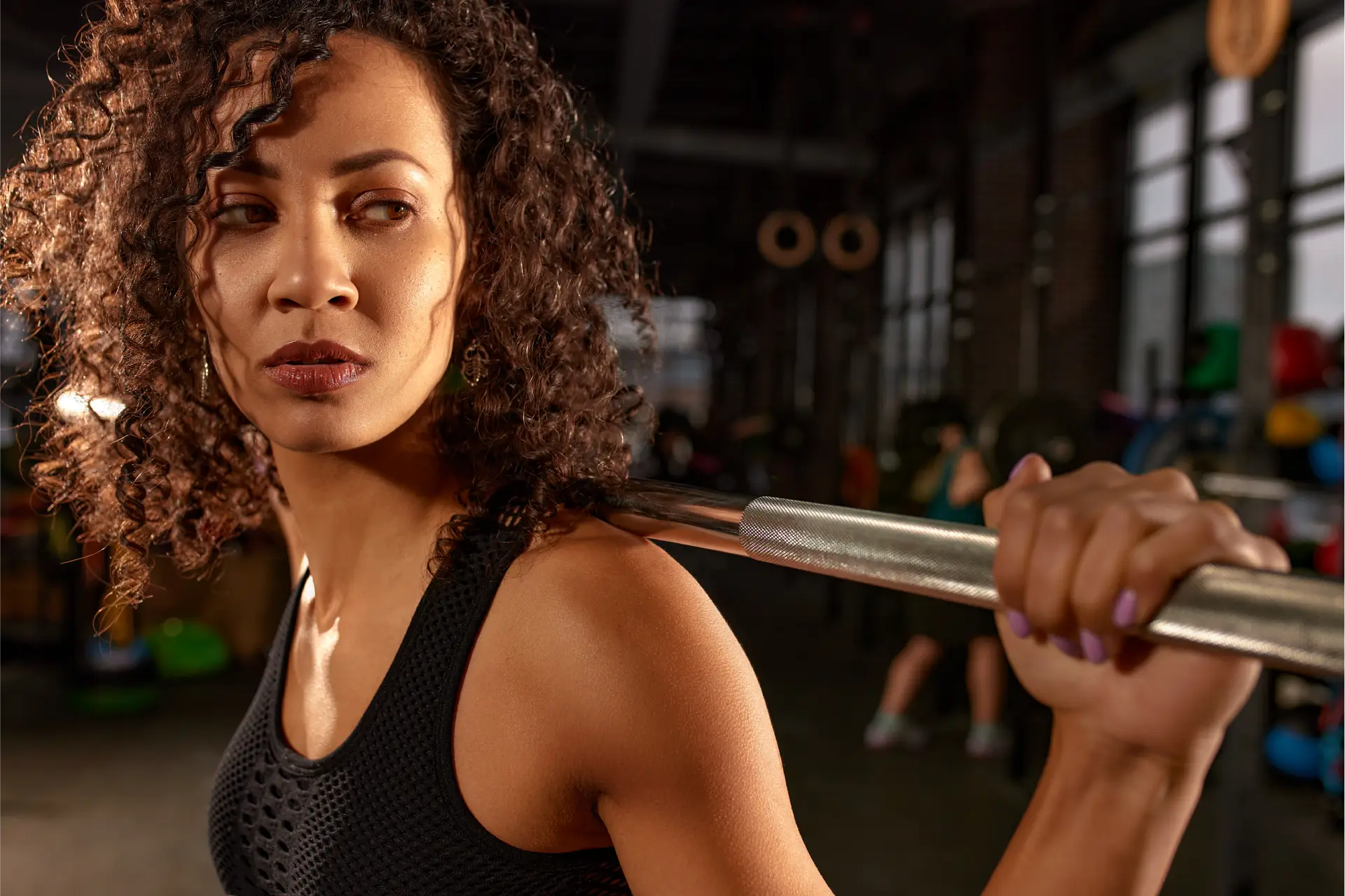 Woman in a gym, holding a barbell in her hands