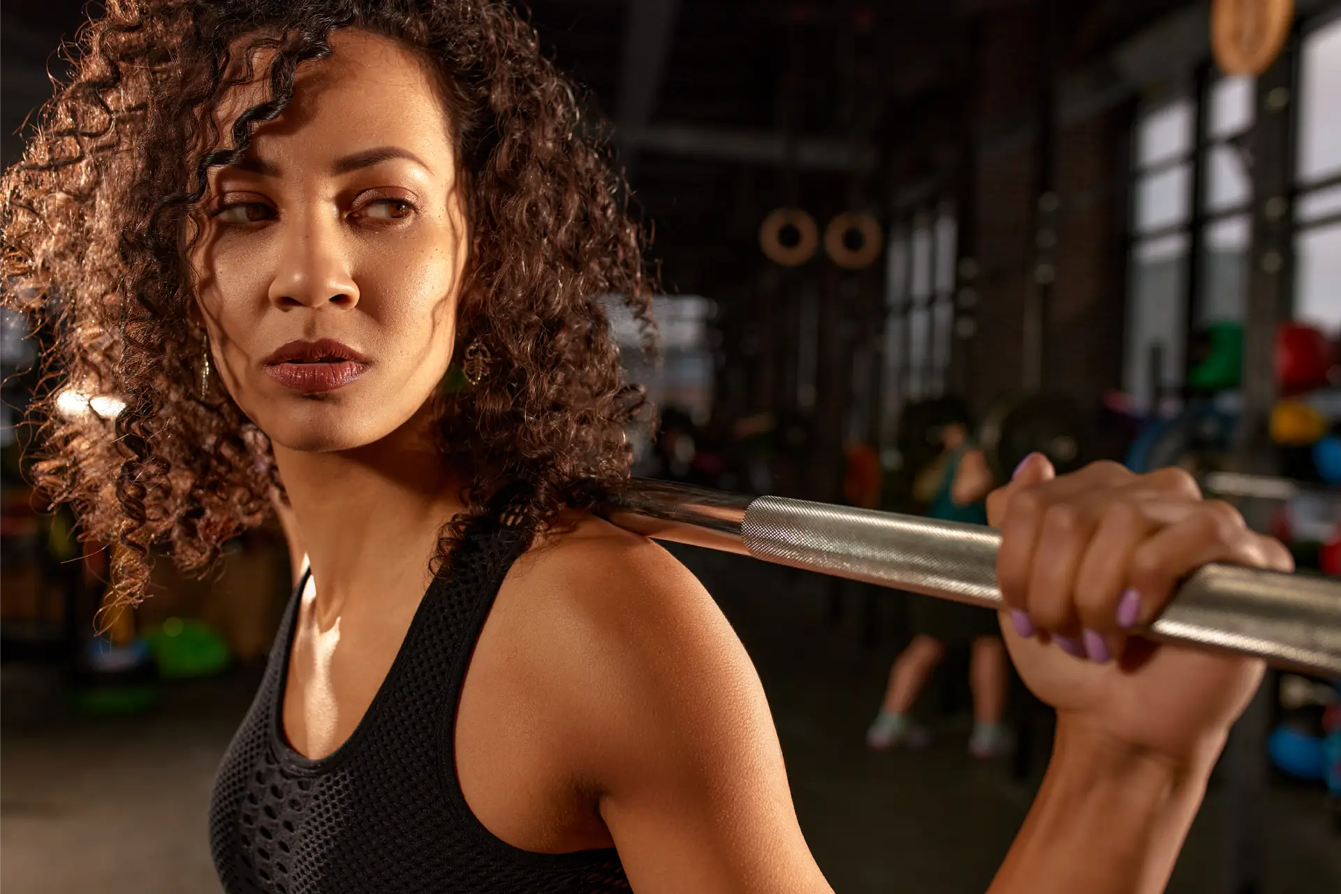 Woman in a gym, holding a barbell in her hands