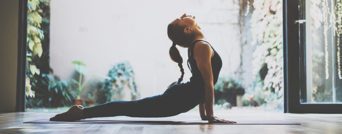 Woman in a yoga pose on a mat in front of a window, with a door on the right side