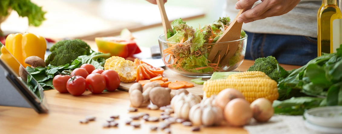 Person preparing a salad on a wooden table