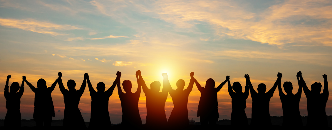 Group of people standing in a circle with their hands raised in the air